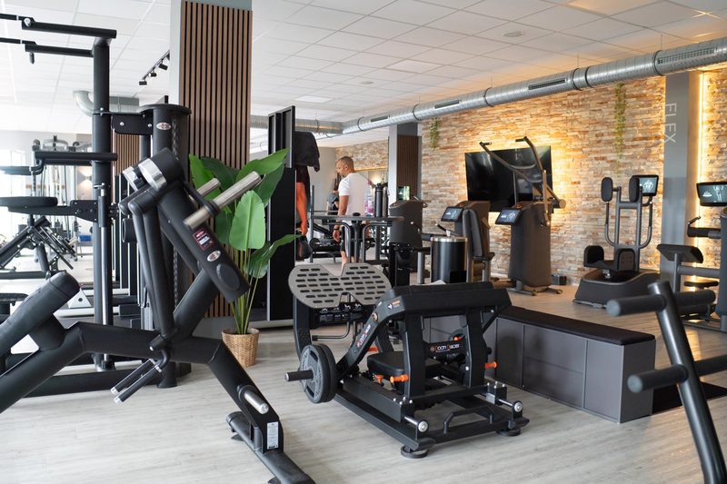 Kraftgeräte und Trainingsfläche vor Natursteinwand im Fit-Inn Heldenbergen